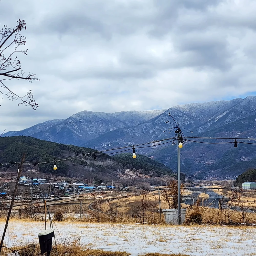 눈이 살짝 쌓인 마당과 겨울 산 능선