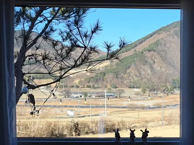 숙소 침실 창문 너머로 보이는 산과 시골 풍경